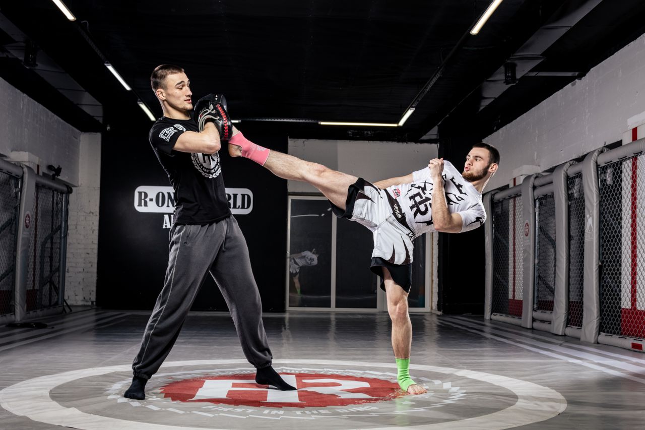 Services Two men demonstrate martial arts techniques in a modern gym setting.