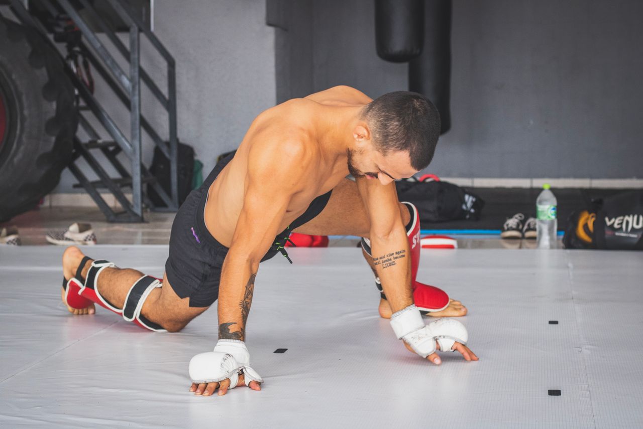 Services A martial arts athlete performing stretching exercises in a gym setting.