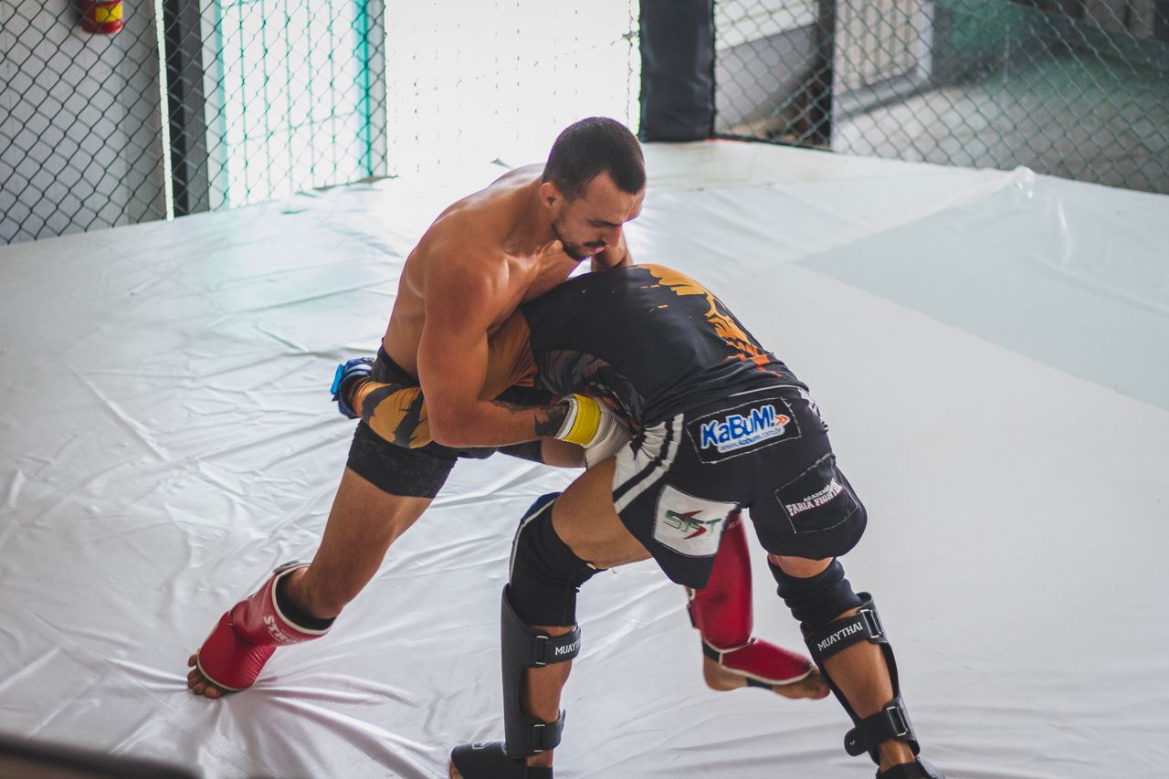 Mastering the First Impression: Your intriguing post title goes here Two MMA fighters grapple intensely in a training gym, showcasing skill and strength.